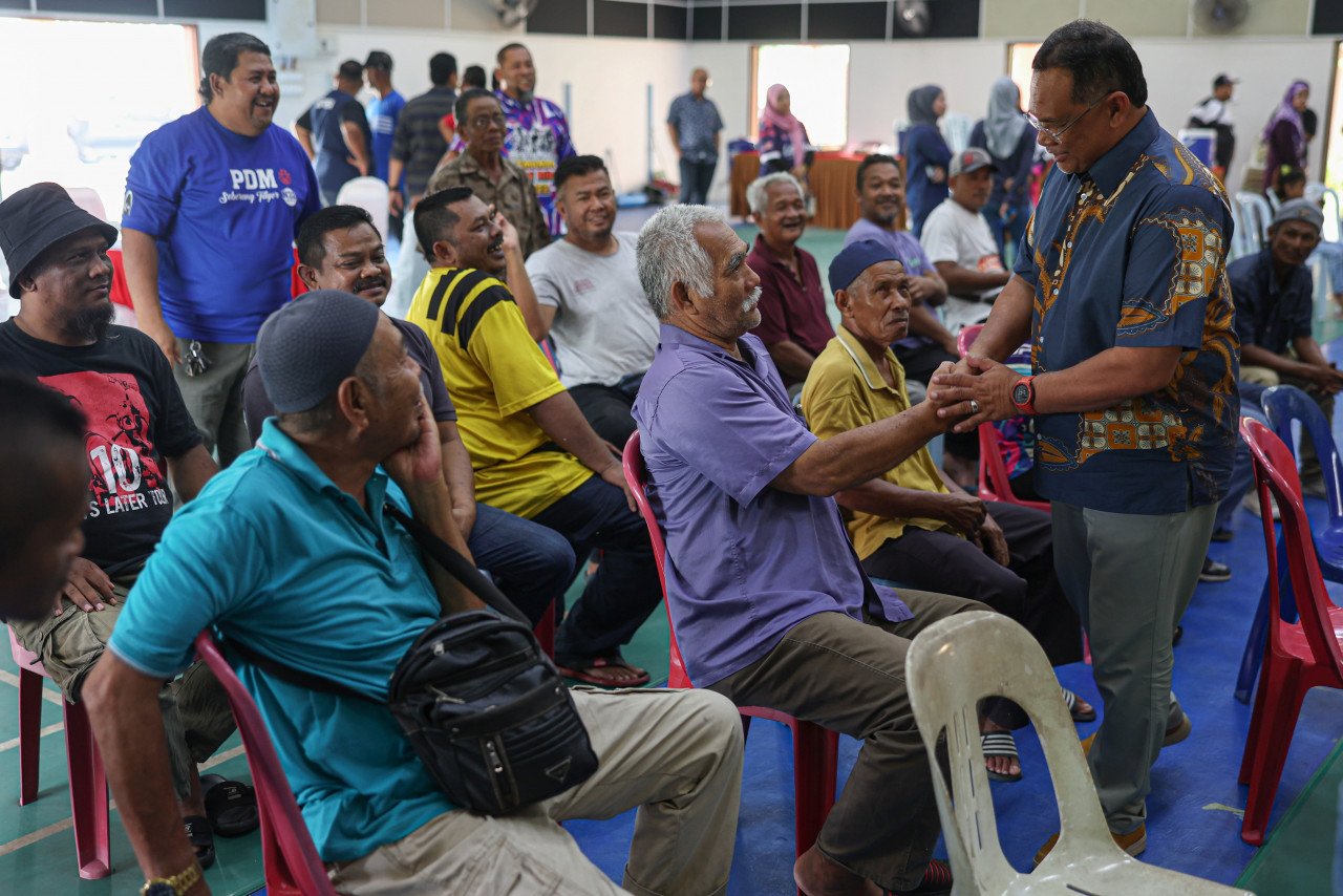 Dr Mohd Zaki Salleh (kanan, berdiri) beramah mesra bersama penduduk setempat ketika tiba di Dewan Sivik Felda Seberang Tayor baru-baru ini