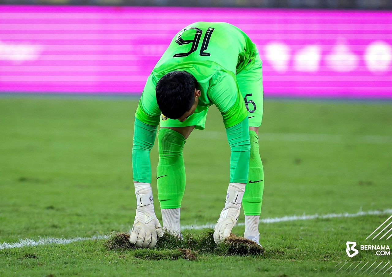 Penjaga gol negara Ahmad Syihan Hazmi Mohamed membaiki semula keadaan rumput yang terkopak - gambar BERNAMA