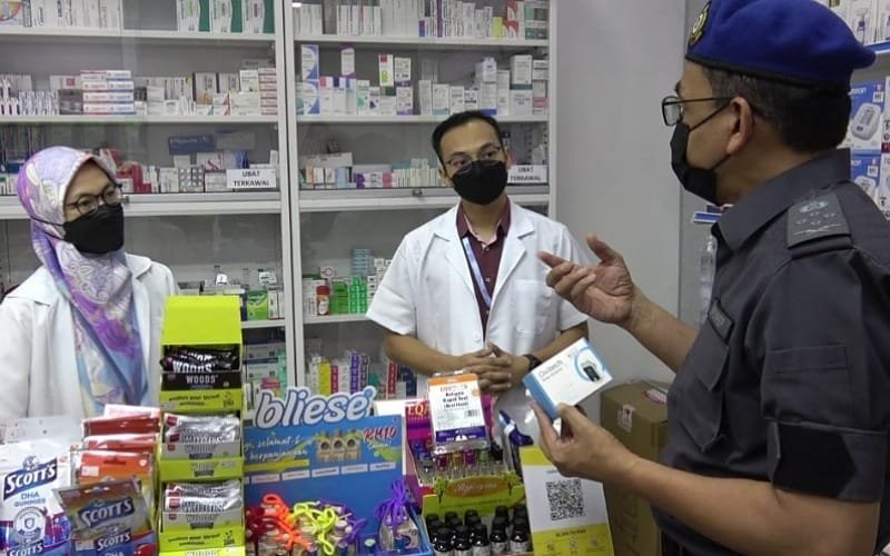 Pengarah (Bahagian Penguatkuasaan) KPDNHEP, Azman Adam (kiri) melakukan pemantauan penjualan kit ujian kendiri COVID-19 di sebuah farmasi di Temerloh, petang semalam.