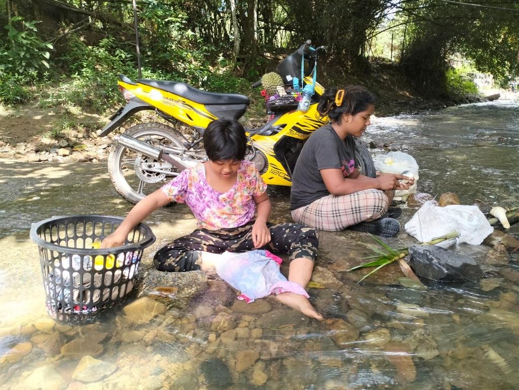 Siti Solehah Hiddayah Rani, 23, (kanan) mencuci rebung untuk dimakan dan dijual manakala anak saudaranya, Siti Zulaikha Mohd Ridzuan membasuh pakaian di sungai akibat masalah air yang melanda Kampung Wang Perah, Jitra.