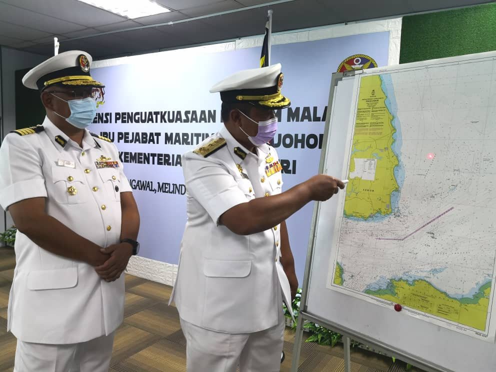 Nurul Hizam (dua dari kiri) menunjukkan peta kawasan perairan yang menjadi tumpuan kapal bersauh secara haram. - Gambar oleh Izlaily Nurul Ain Hussein 