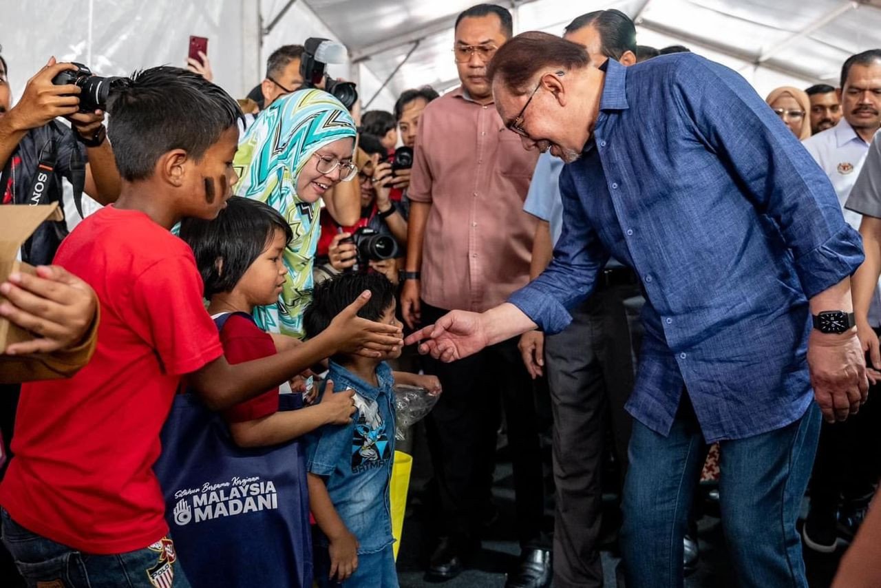 Perdana Menteri (kanan) menyantuni pengunjung cilik ketika melawat Program Setahun Bersama Kerajaan Madani