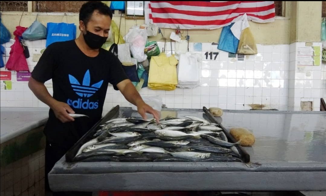 Peniaga ikan di Pasar Besar Kuantan sedang menyusun ikan yang dijual di gerai miliknya.