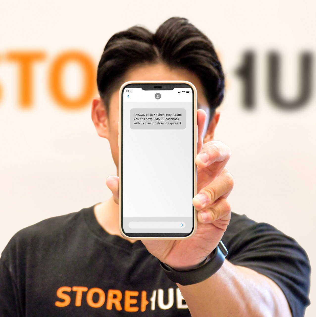 Pekerja StoreHub memegang telefon untuk menunjukkan peringatan SMS untuk Pulangan Tunai. - Gambar daripada voxeureka.com