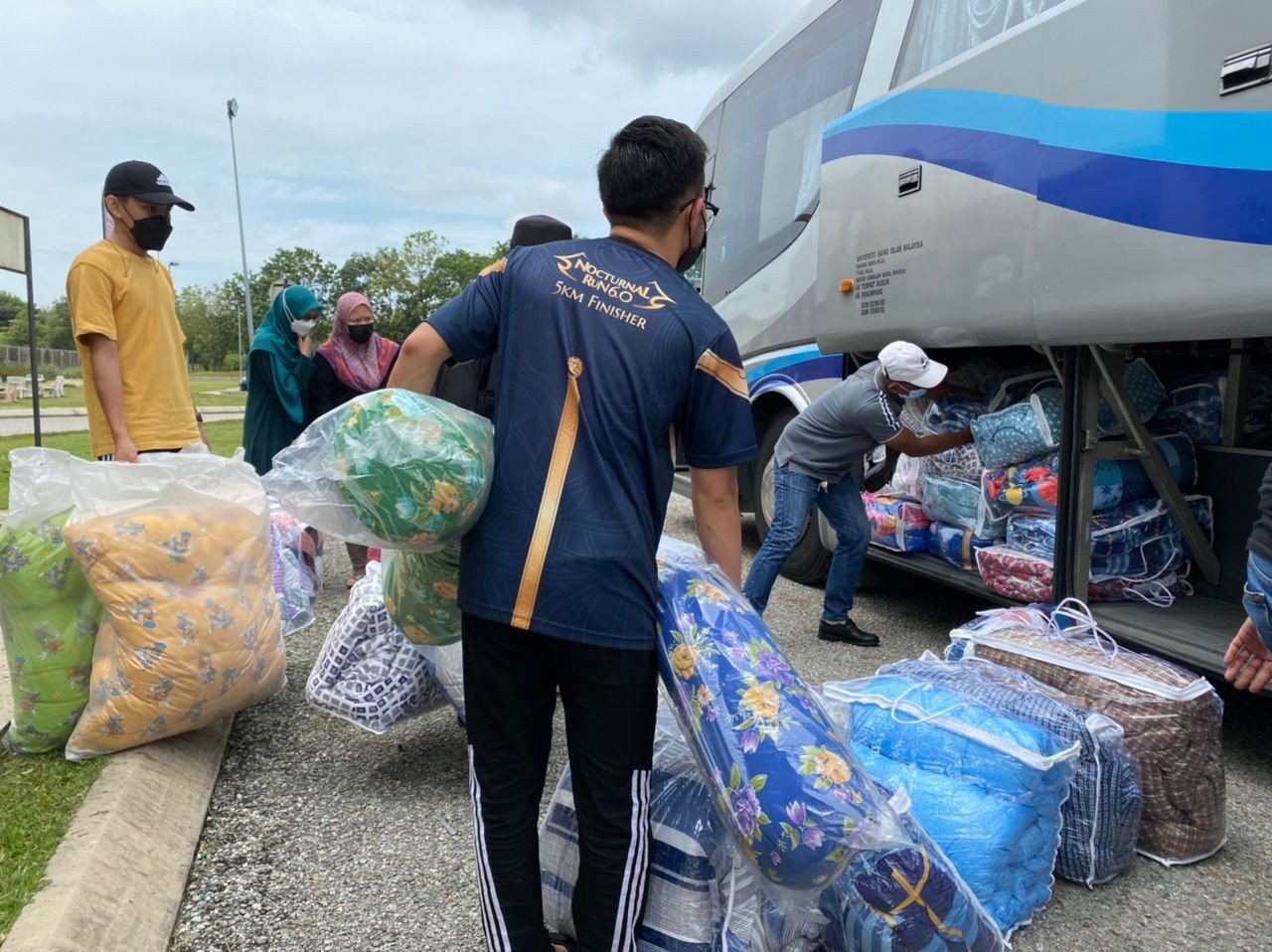Peserta program Misi USIMPrihatin memasukkan barangan keperluan asas ke dalam bas untuk diagihkan kepada mangsa banjir di Kemaman, Terengganu.