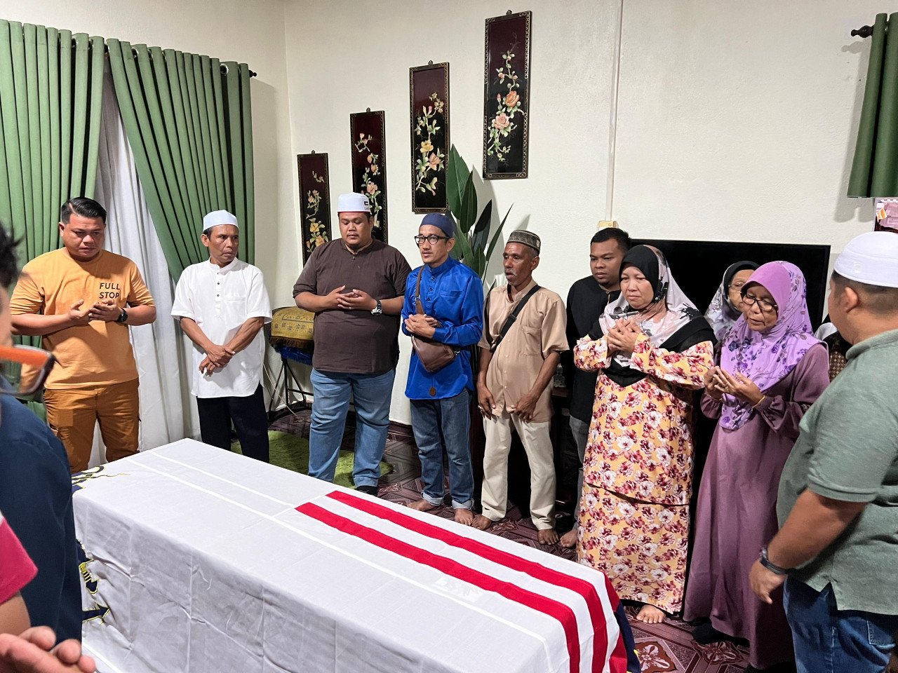 Ahli keluarga Allahyarham mendoakan kesejahteraan Muhammad Faisol Tamadun ketika jenazahnya tiba di rumah kakaknya di Kampung Tanjung - gambar Rafisqi Radhi
